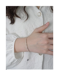 Vue détaillée d'un bracelet cordelette en argent massif S925 au poignet d'une femme