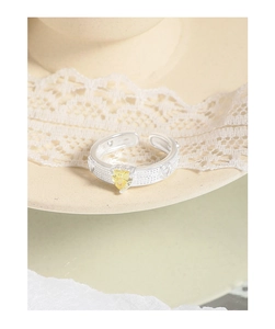 Close-up of heart-shaped yellow gemstone ring with pavé setting and silver adjustable band