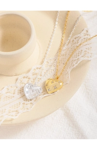 Close-up of gold and silver heart necklaces with starburst engraving and zircon detail