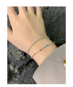 Detail of silver double-layer bracelet with rainbow beads on model against stone background