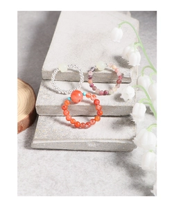 Macro shot of handmade crystal beaded rings on stone slabs with white lily of the valley