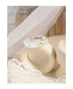 Macro shot of silver ring featuring a yellow heart gemstone and pavé setting texture