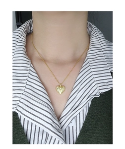 Close-up of a gold heart pendant necklace with star-set cubic zirconia on a model