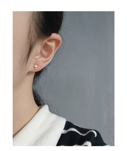 Close-up of a gold mushroom stud earring with pavé zircon crystals on a model's ear