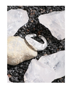 Macro detail of silver ring with irregular lava texture on dark stones background