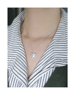 Close-up of heart pendant necklace with star engraving on a model with striped shirt