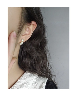 Vue détaillée de trois perles blanches en courbe verticale sur une boucle d'oreille S925