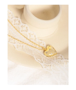 Close-up of gold heart pendant with inlaid cubic zirconia on elegant lace background