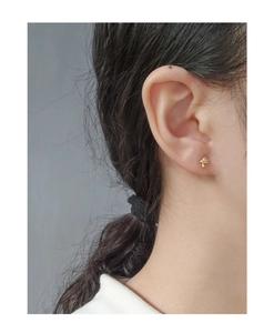 Detail of mushroom-shaped gold stud earrings with cubic zirconia on a model's ear