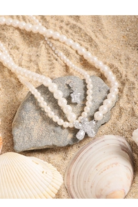 Detail of three-layer pearl necklace with a sparkling diamond-set flower and star pendant