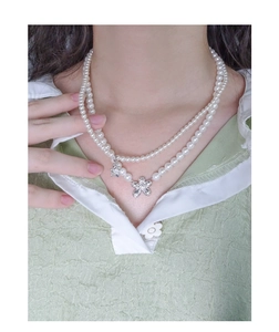 Close-up of double layer pearl necklace with flower pendants on a model wearing green
