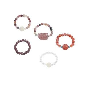 Set of five crystal beaded elastic rings with gemstone charms on white background