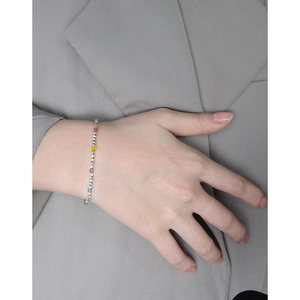 Minimalist S925 silver beaded bracelet with colorful crystal accents on a grey suit sleeve