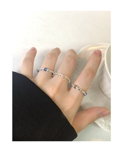 Dettaglio dell'anello fatto a mano con perle e cristalli blu e viola su mano