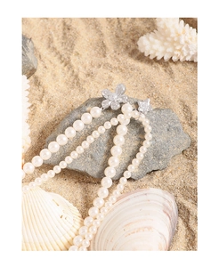Close-up of double-layer pearl necklace with a silver floral clasp on beach sand