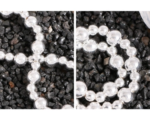 Macro shot of silver beaded bracelet with polished metallic spheres on dark stone background