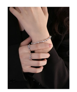 Detailed view of polished S925 silver beaded bracelet and minimalist rings for women