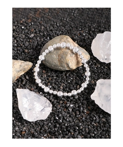 Close-up of a polished S925 silver beaded bracelet displayed on natural stones