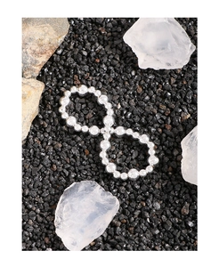 Detail of silver S925 infinity charm bracelet with polished round beads on crystal background