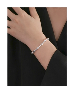 Close-up of minimalist sterling silver bead bracelet worn on wrist over black suit