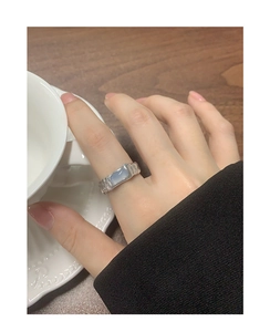 Detailed view of an S925 silver ring with irregular texture and blue agate on a finger