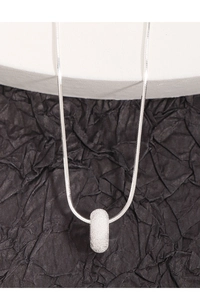Macro shot of silver-toned frosted cylinder pendant on a sleek snake chain necklace