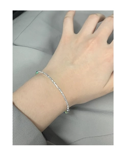 Macro view of minimalist silver chain bracelet with radiant green crystal beads detail