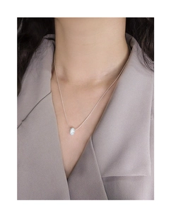 Macro shot of sparkling doughnut pendant necklace on collarbone over khaki blazer