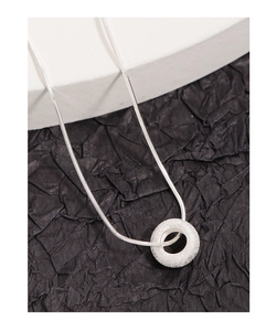 Macro shot of silver donut pendant with frosted texture on a delicate snake chain