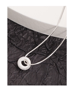 Macro shot of silver donut pendant with frosted texture on flat snake chain necklace
