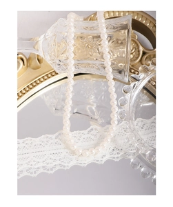 Macro view of lustrous white round pearl necklace on a vintage golden frame background