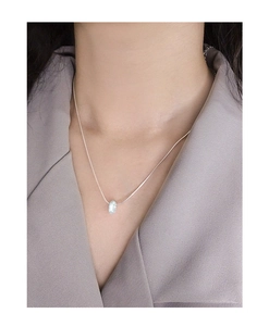 Close-up of minimalist silver donut pendant necklace with sparkling texture on a model