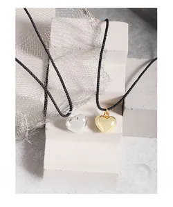 Gros plan de pendentifs en forme de cœur en or et argent avec cordon noir sur pierre