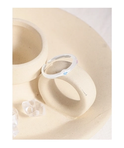 Detail of S925 silver wave ring with blue and pink cubic zirconia on a ceramic cup handle