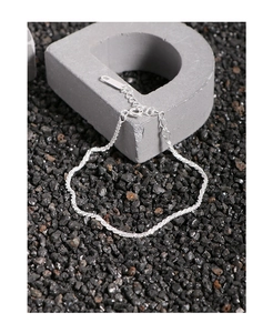 Macro detail of a 925 sterling silver chain bracelet with lobster clasp on grey texture