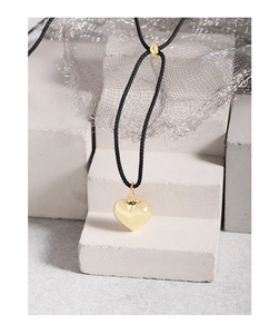 Gros plan d'un pendentif cœur en or poli avec un collier en cordon noir réglable