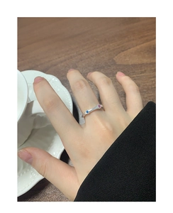 Detailed close-up of a silver ring with blue and pink cubic zirconia on a female finger