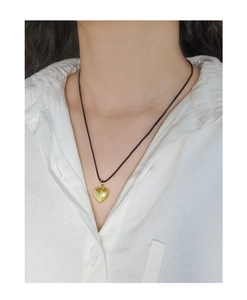 Gros plan d'un collier avec pendentif coeur doré et cordon noir élégant