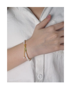 Dettaglio del bracciale di perle in argento S925 al polso con lucentezza e chiusura d'oro