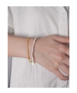 Dettaglio del bracciale a catena in argento dorato abbinato a perle naturali bianche