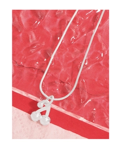 Vue macro d'un pendentif cerise en argent avec chaîne serpent sur fond rouge texturé
