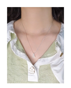 Gros plan d'un collier pendentif cerise en argent minimaliste sur mannequin et chemise