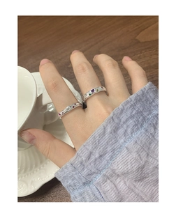 Detail of silver rings with liquid metal texture and colorful zircon heart gemstones