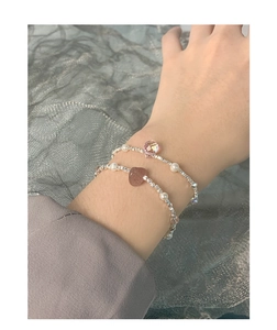 Detail of silver beaded bracelets featuring pink strawberry crystals and small pearls