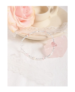 Detailed macro of irregular strawberry quartz and pearl beaded silver bracelet on lace