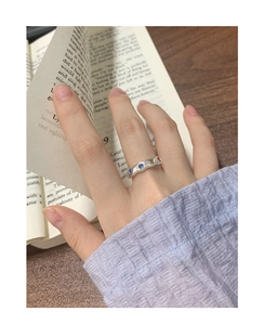 Detail of wavy S925 silver ring with colorful stones worn while reading a book