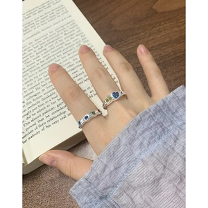 Elegant S925 silver rings with heart-shaped blue and green gemstones on vintage book