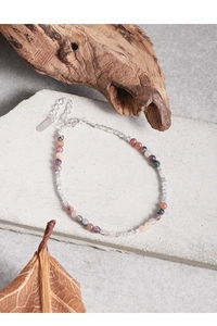 Macro shot of S925 sterling silver tag and multicolored tourmaline beaded bracelet