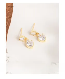 Gros plan de boucles d'oreilles cœur dorées avec zircon blanc sur papier beige