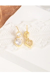 Gros plan de boucles d'oreilles cœur en argent S925 et zircon sur fond de dentelle